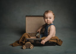 jolie bébé dans une valise avec voiture en bois