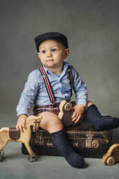 enfant avec casquette et chaussette assis sur une valise vintage