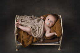 un petit bebe de 8 mois dans un petit lit en fer