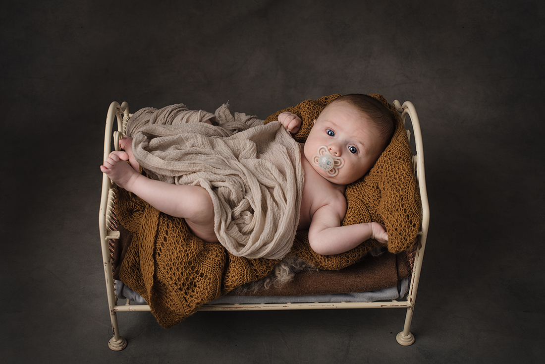 un petit bebe de 8 mois dans un petit lit en fer